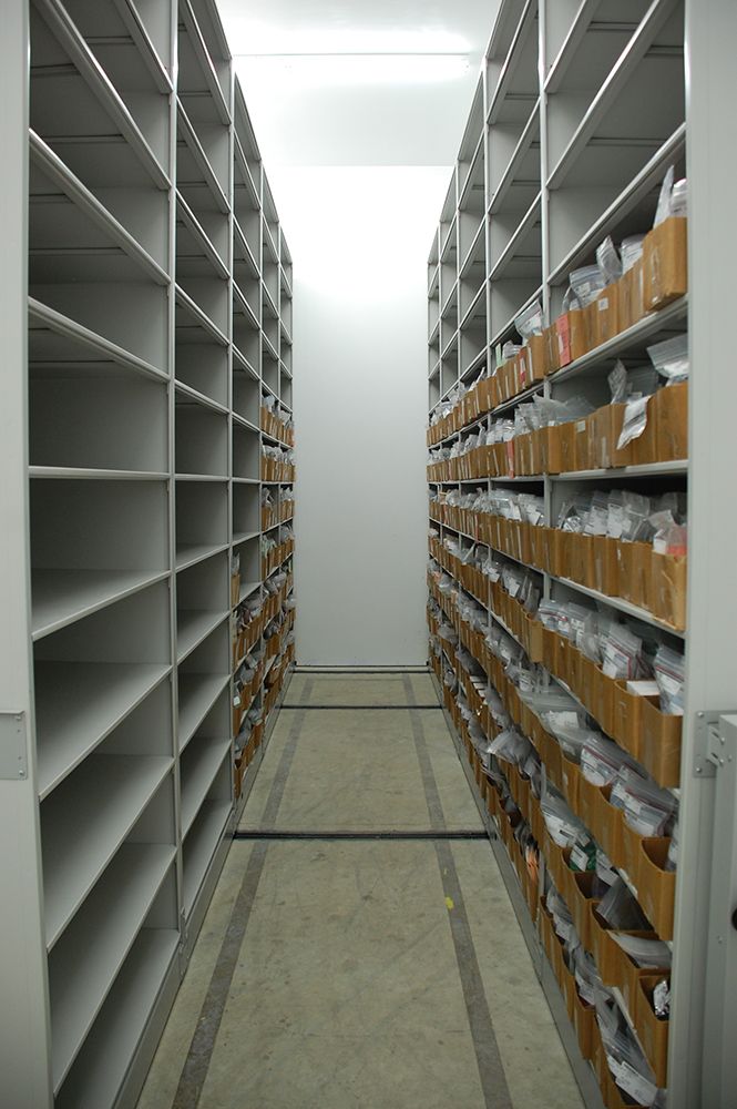 Aisle of high-density mobile storage system with many boxes on the shelves