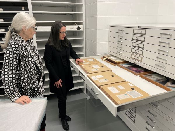 Two women opening a Spacesaver Nantucket system holding stored art