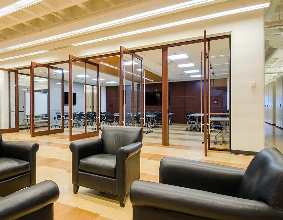 campus library with leather chairs and a presentation room behind them