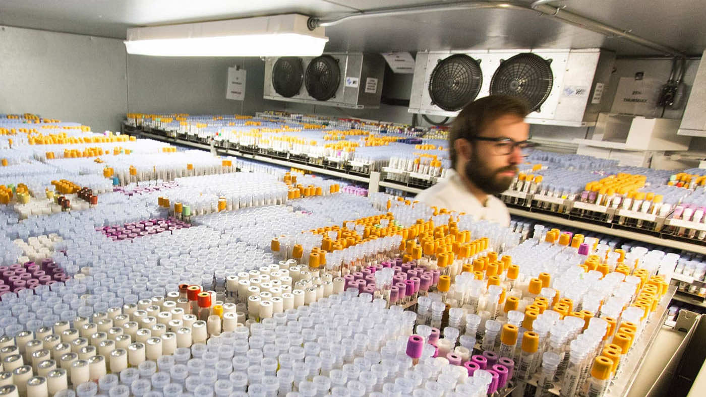 Doctor walking through an aisle of refrigerated samples on mobile system in pathology lab