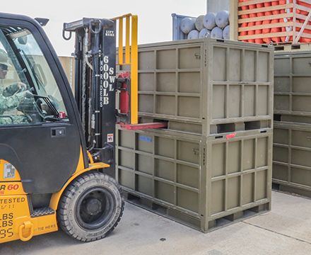Forklift picking up an army green Spacesaver rapid readiness box