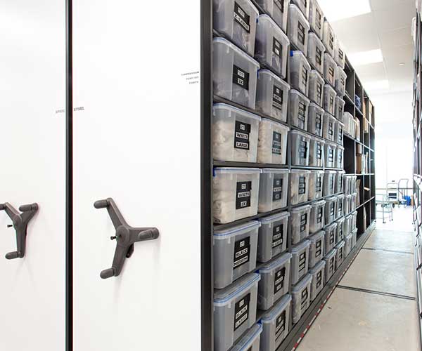 Football gear in totes stored on a mechanical assist mobile shelving system