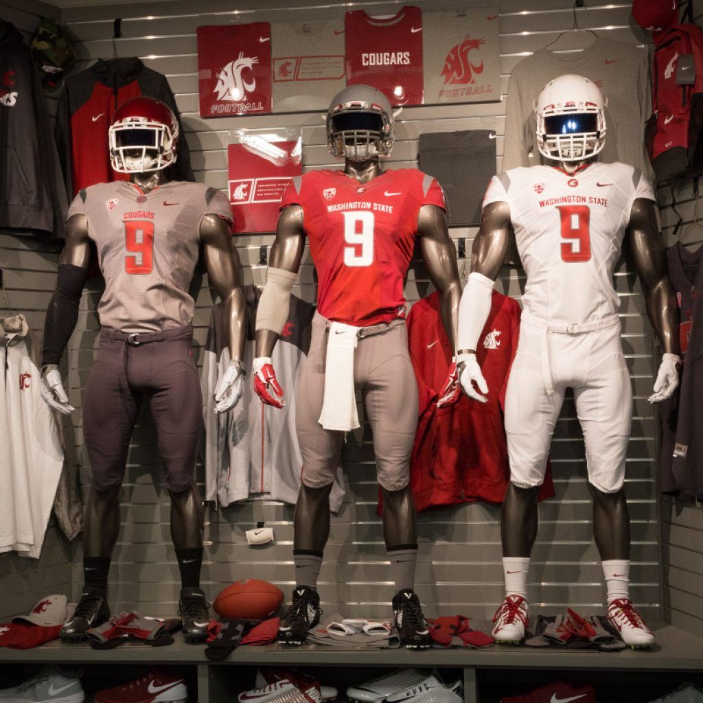 Mannequins wearing three different football uniforms on display with various shirts and apparel behind them