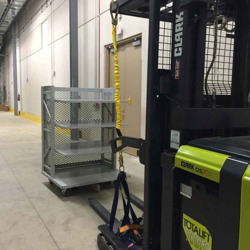 Forklift and wheeled caddy holding Spacesaver shelving