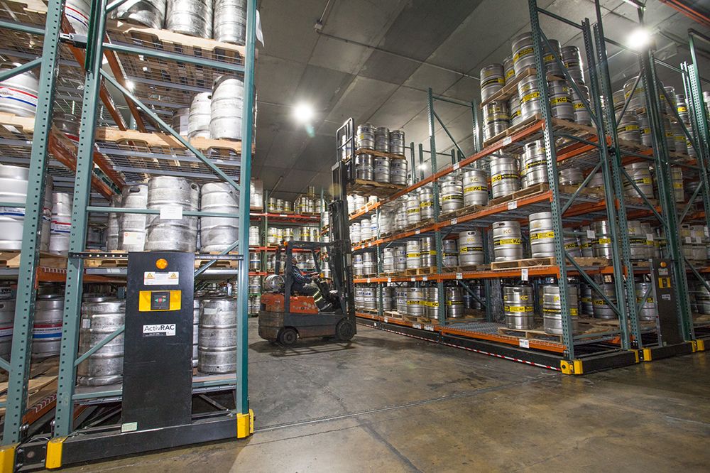ActivRAC powered mobile racking system holding beer kegs and a forklift in the middle of the aisle