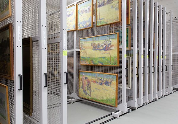 Multiple paintings hanging on mobile floor mounted art racks