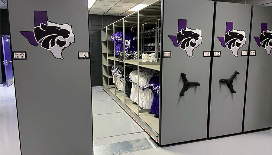 high school football equipment room with mechanical assist system featuring school's logo
