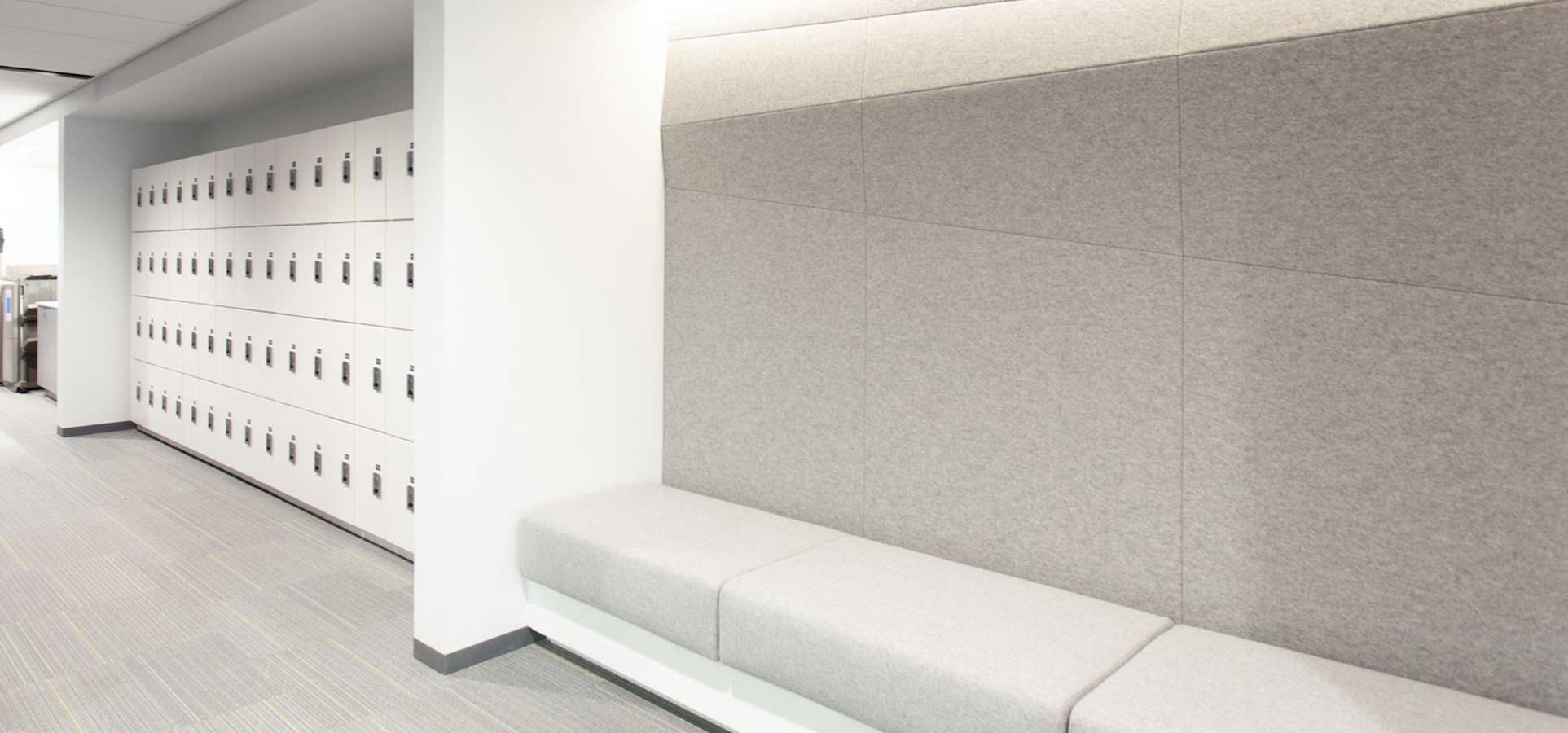 Wall of day use lockers in a hallway next to a padded bench