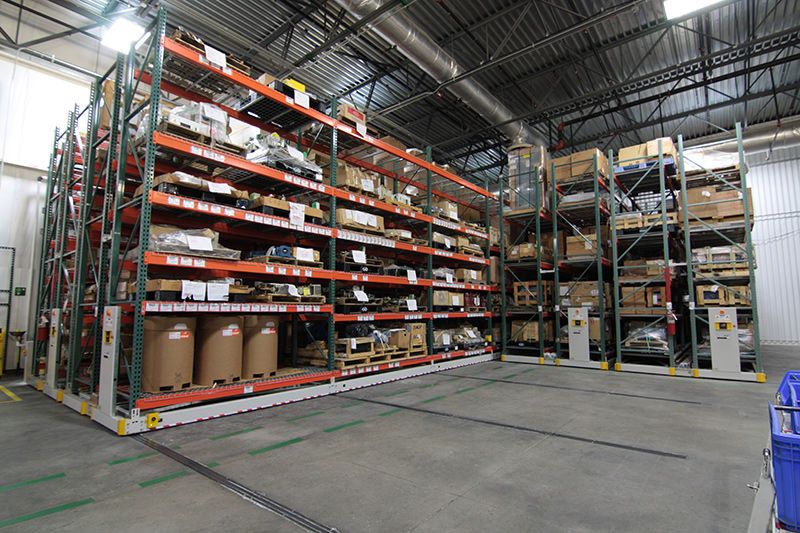 auto parts, boxes, and pallets on a powered mobile racking system in a warehouse
