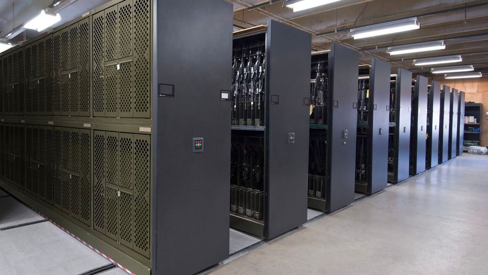 Military armory featuring dark green Universal Weapons Racks mounted mobile storage system
