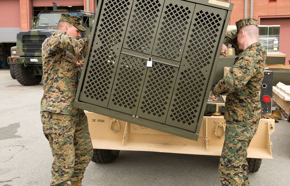 Soldiers lifting Universal Weapons Rack onto the back of a tan truck