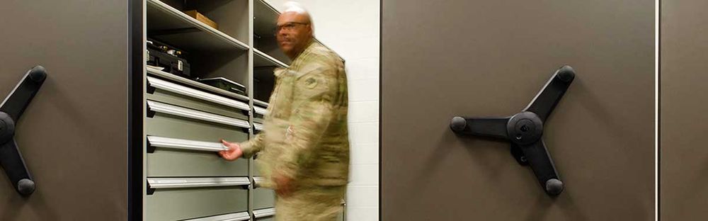 soldier pulling out a drawer in the aisle of a spacesaver mechanical assist solution