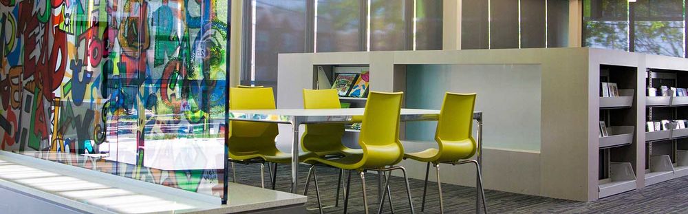 public library table and chairs next to book case island and painted glass wall