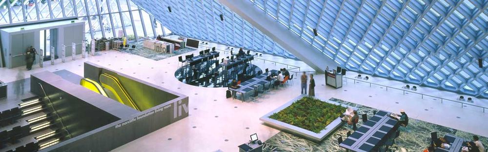 lobby of a library with large glass window walls and indoor garden
