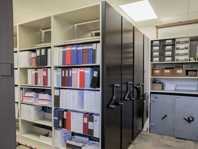 mechanical assist shelving system holding binders and office supplies