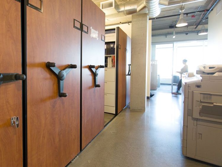 mechanical assist shelving system holding office supplies