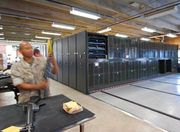 Soldier checking rifles in armory with Spacesaver UWRs on mobile systems 