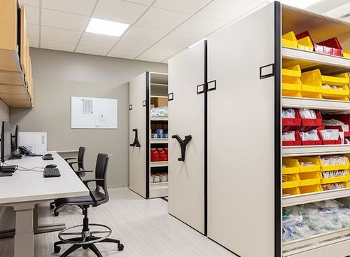 mechanical assist mobile shelving in a pharmacy with bins