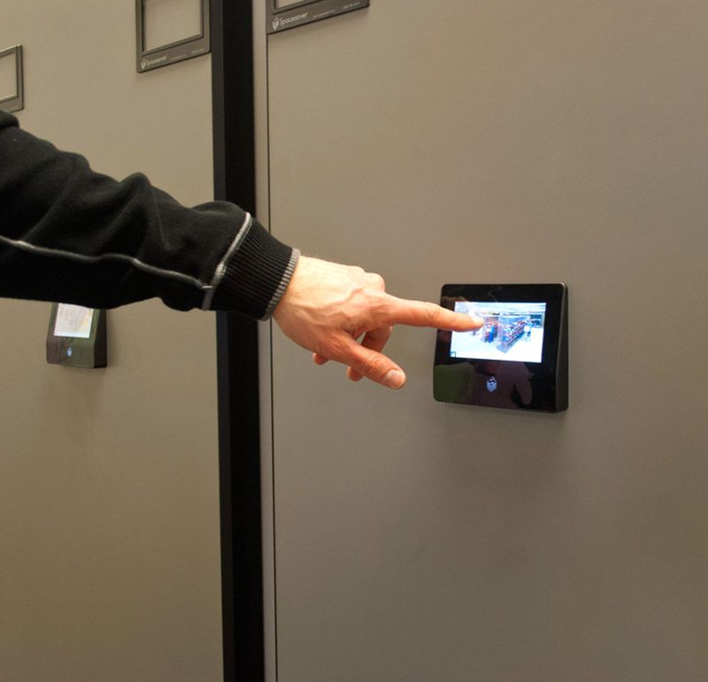 Person pointing to the touchpad controls on a powered mobile storage system