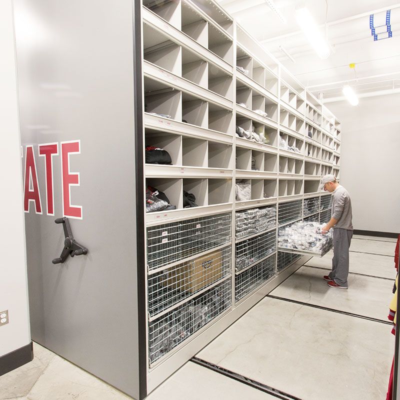 Wire baskets and shelves holding football equipment on a mechanical assist high-density mobile storage system